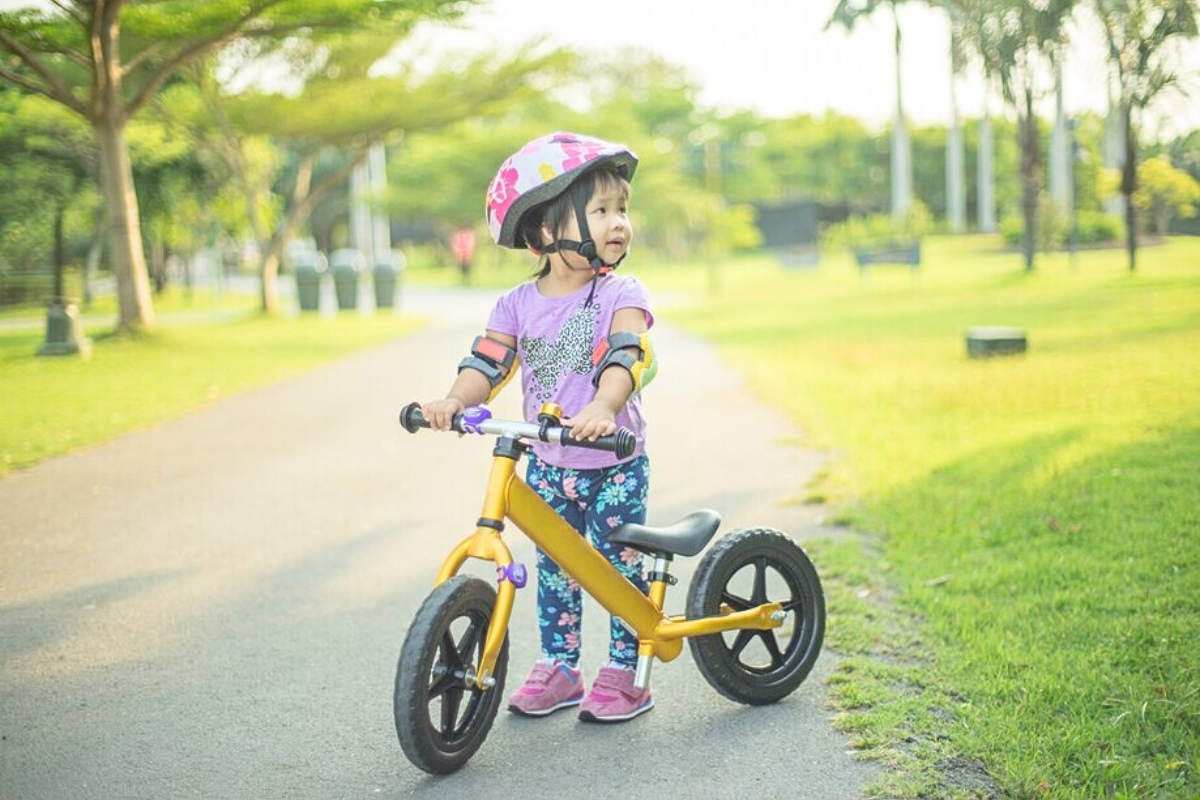 Bé gái bên chiếc xe thăng bằng, cùng đồ bảo hộ an toàn